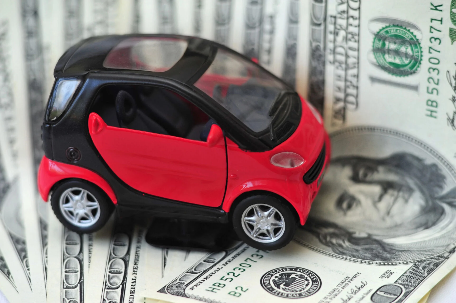 Red toy car sits on top of money