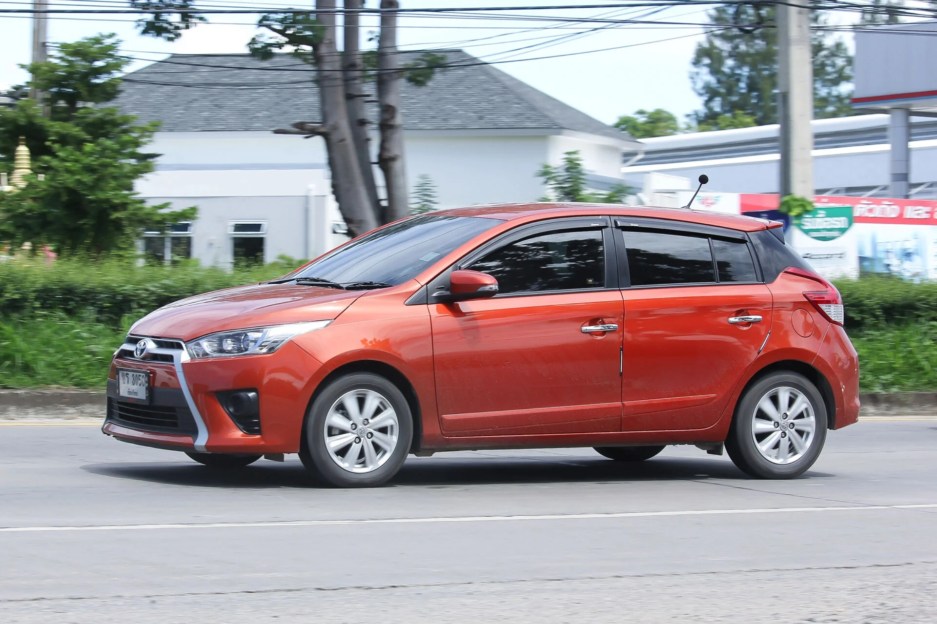 A dark orange Toyota Yaris driving town the road.