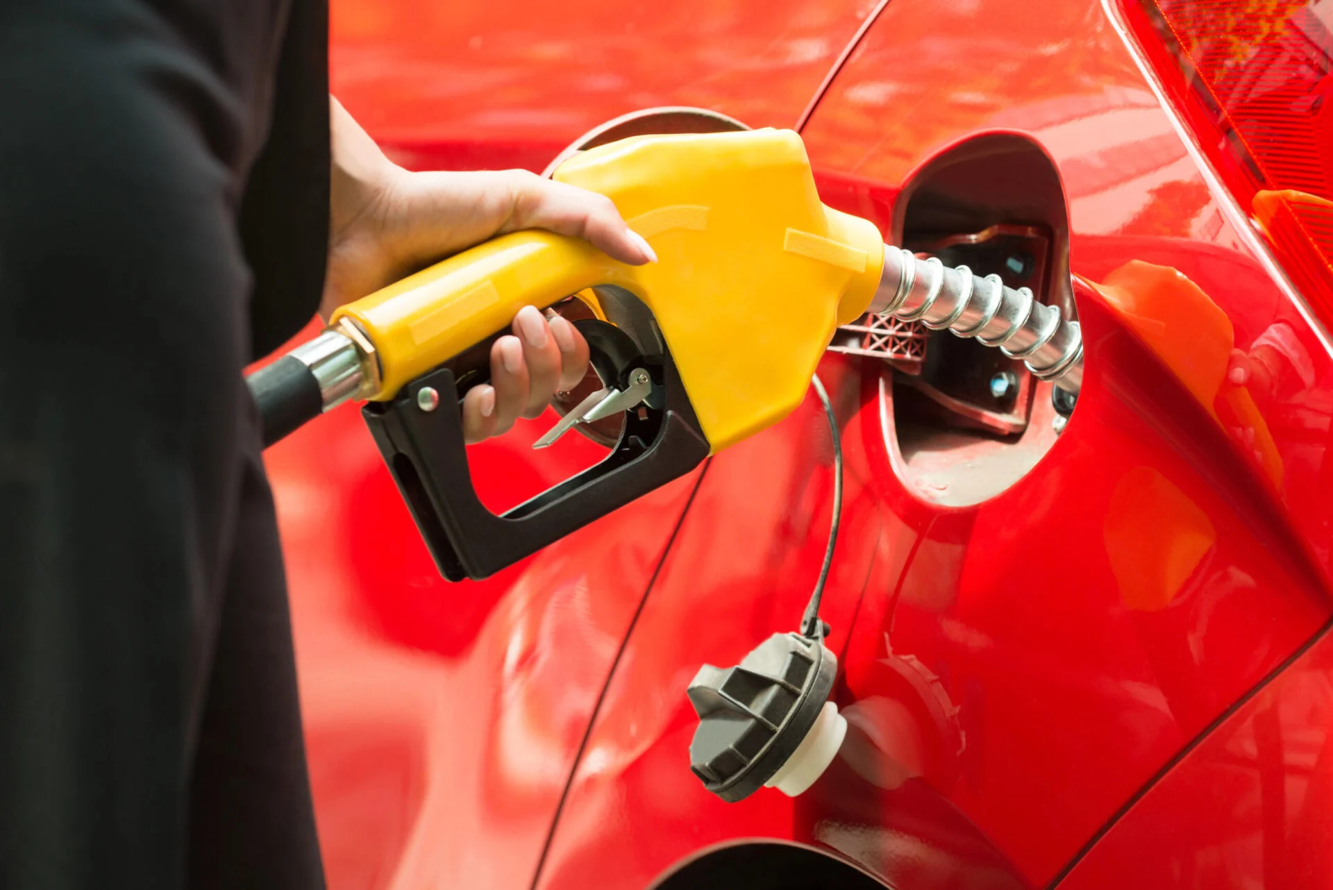 Person filling gas tank of a red car