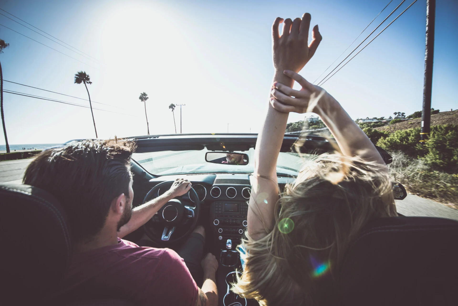 Couple driving in a convertible car near the ocean