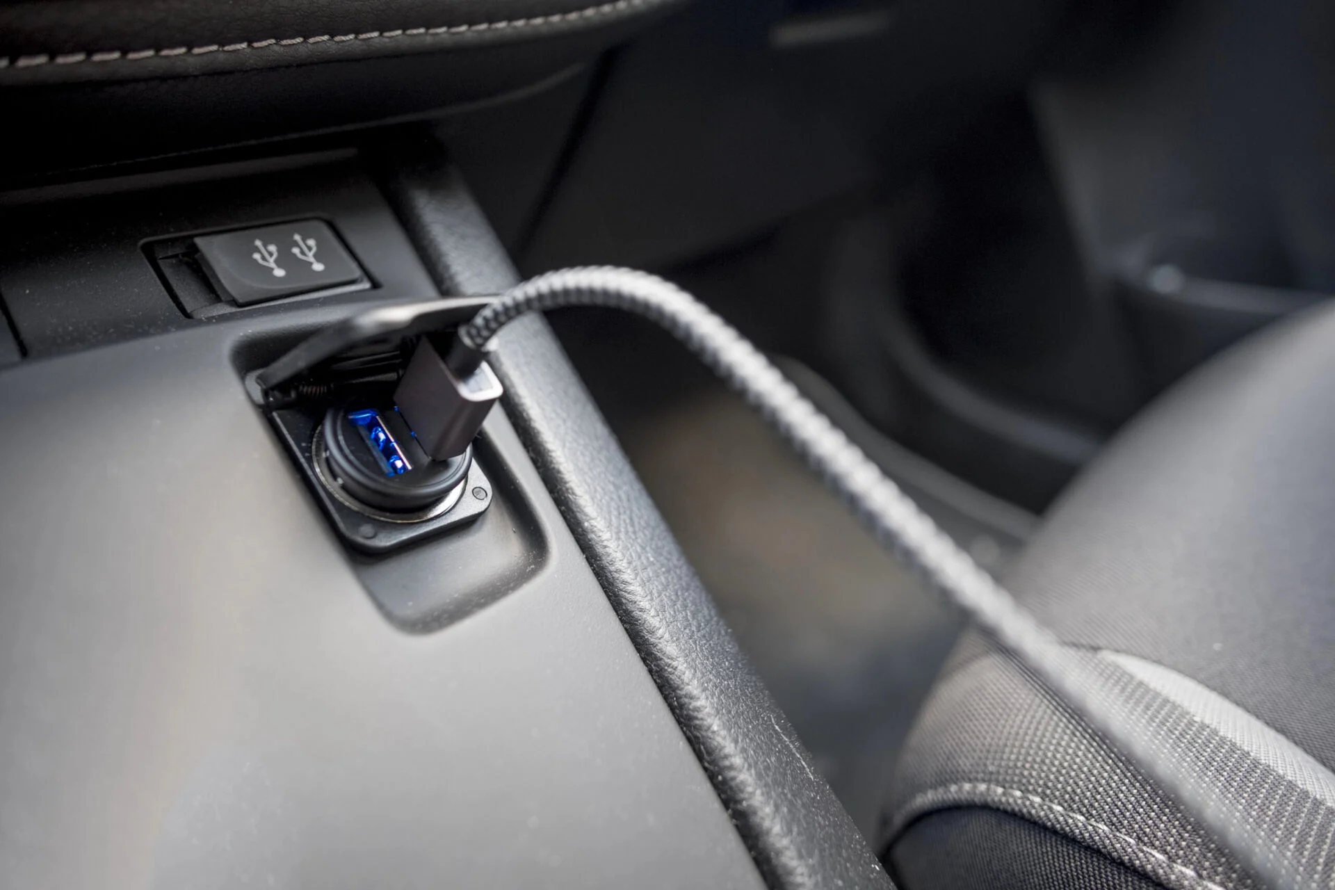 Closeup of a USB port inside a car with the cord coming out