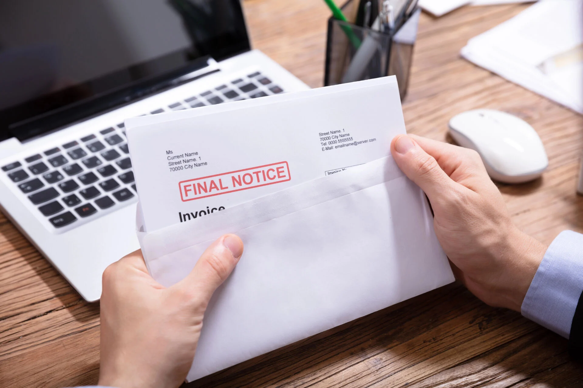 Person opening an envelop with a 'final notice' letter in it
