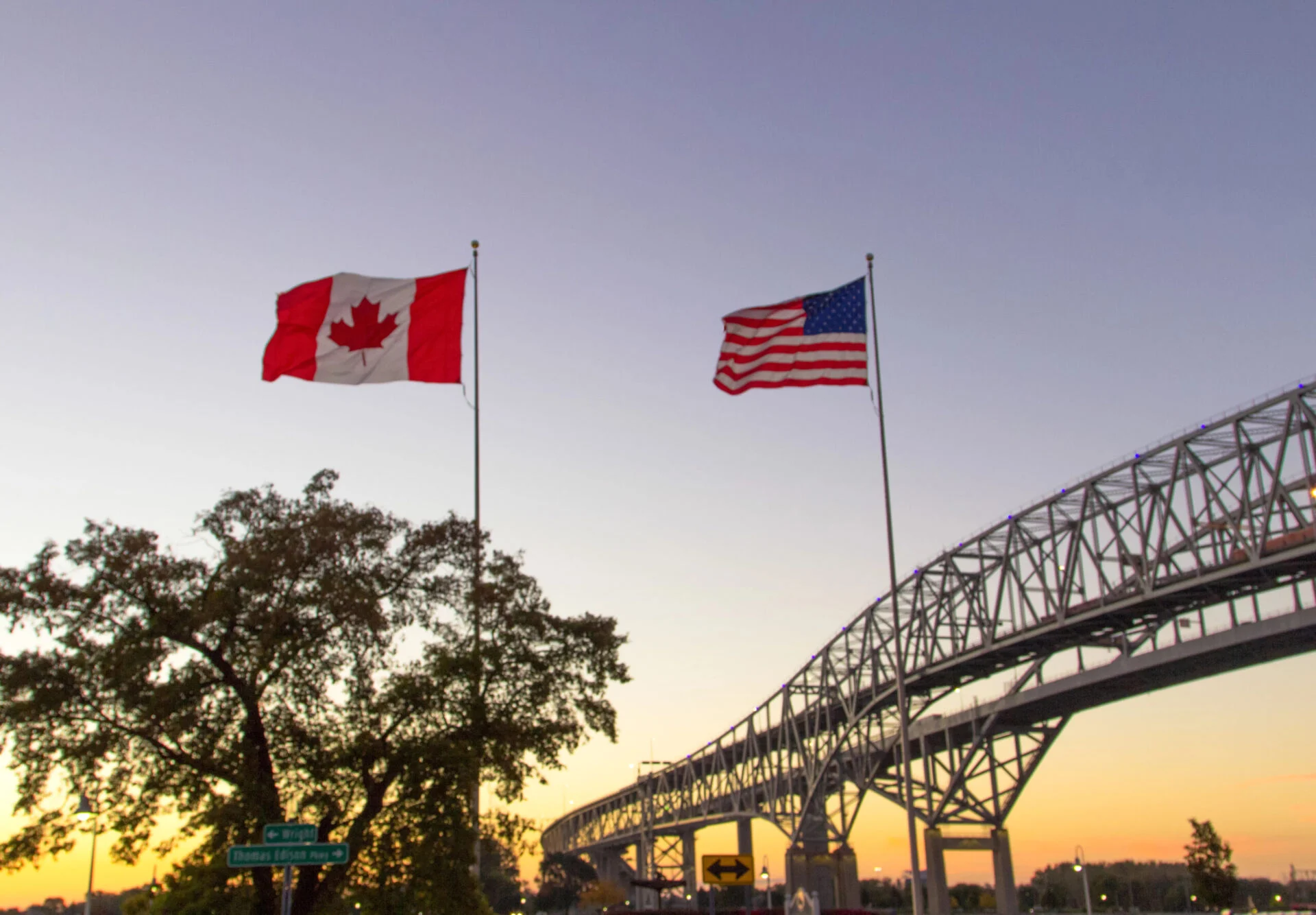 Canada-USA Border at sunset with flags.