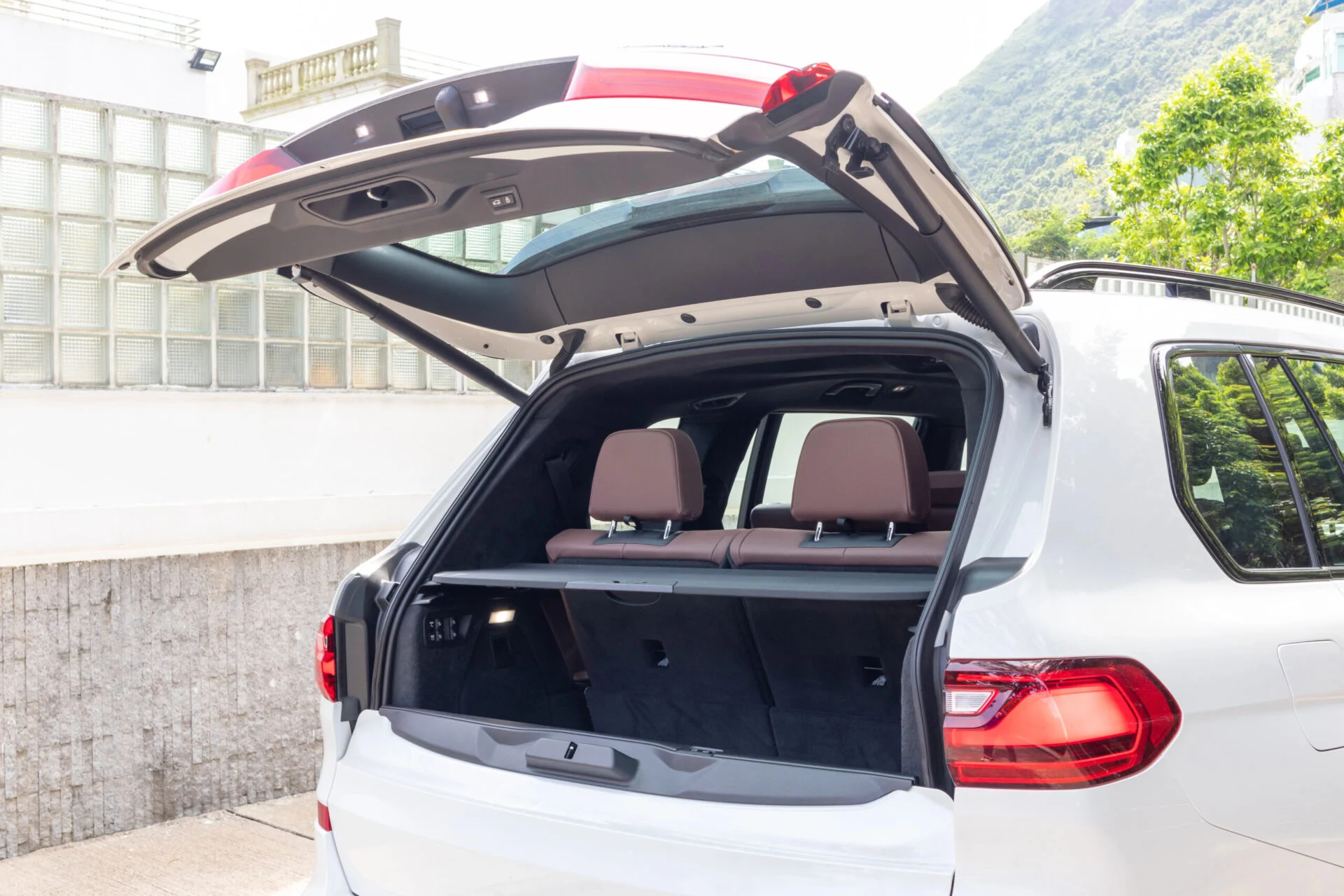 A white vehicle with the rear hatchback opened up while parked near a building