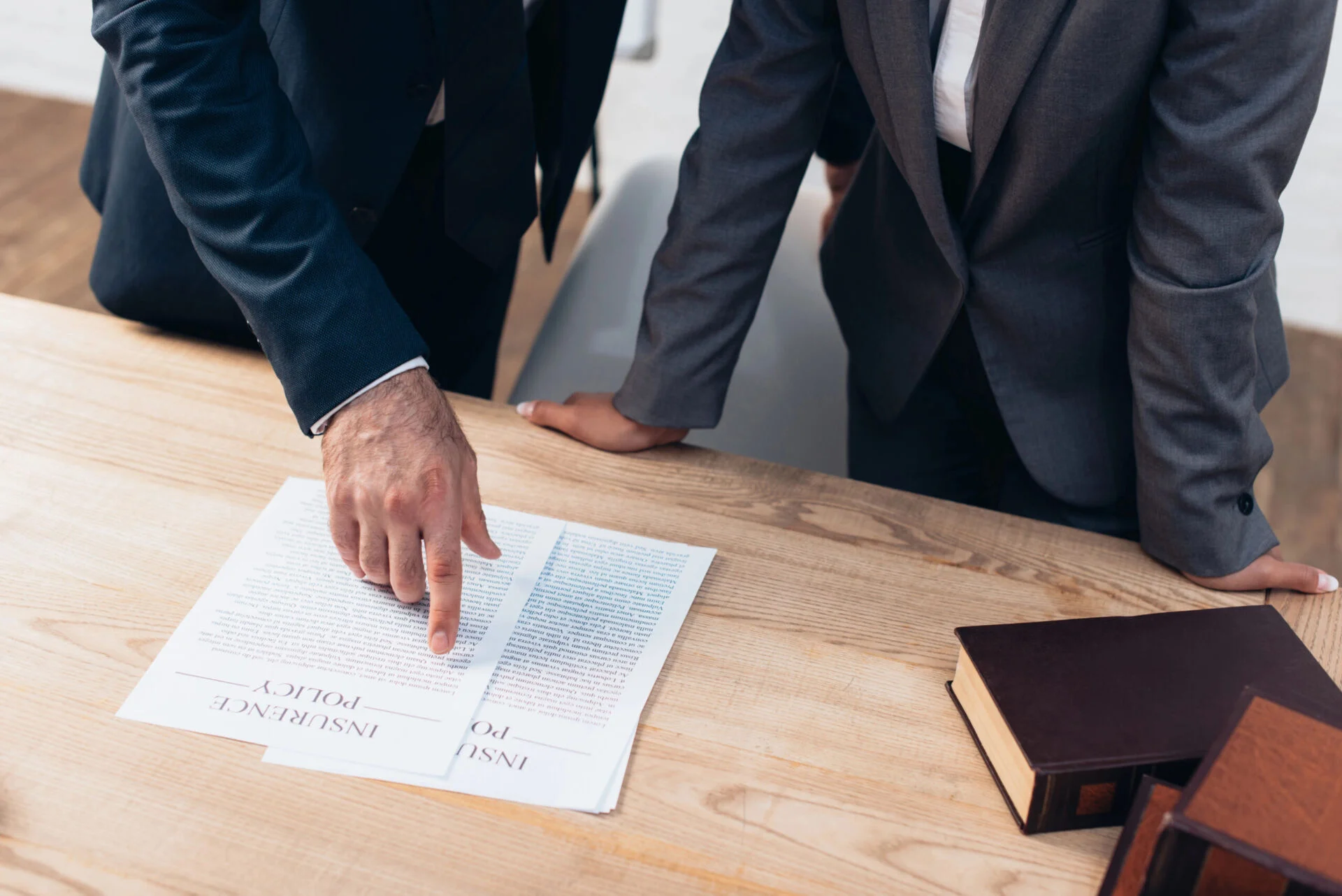 Two people in suits look at insurance documents on a table