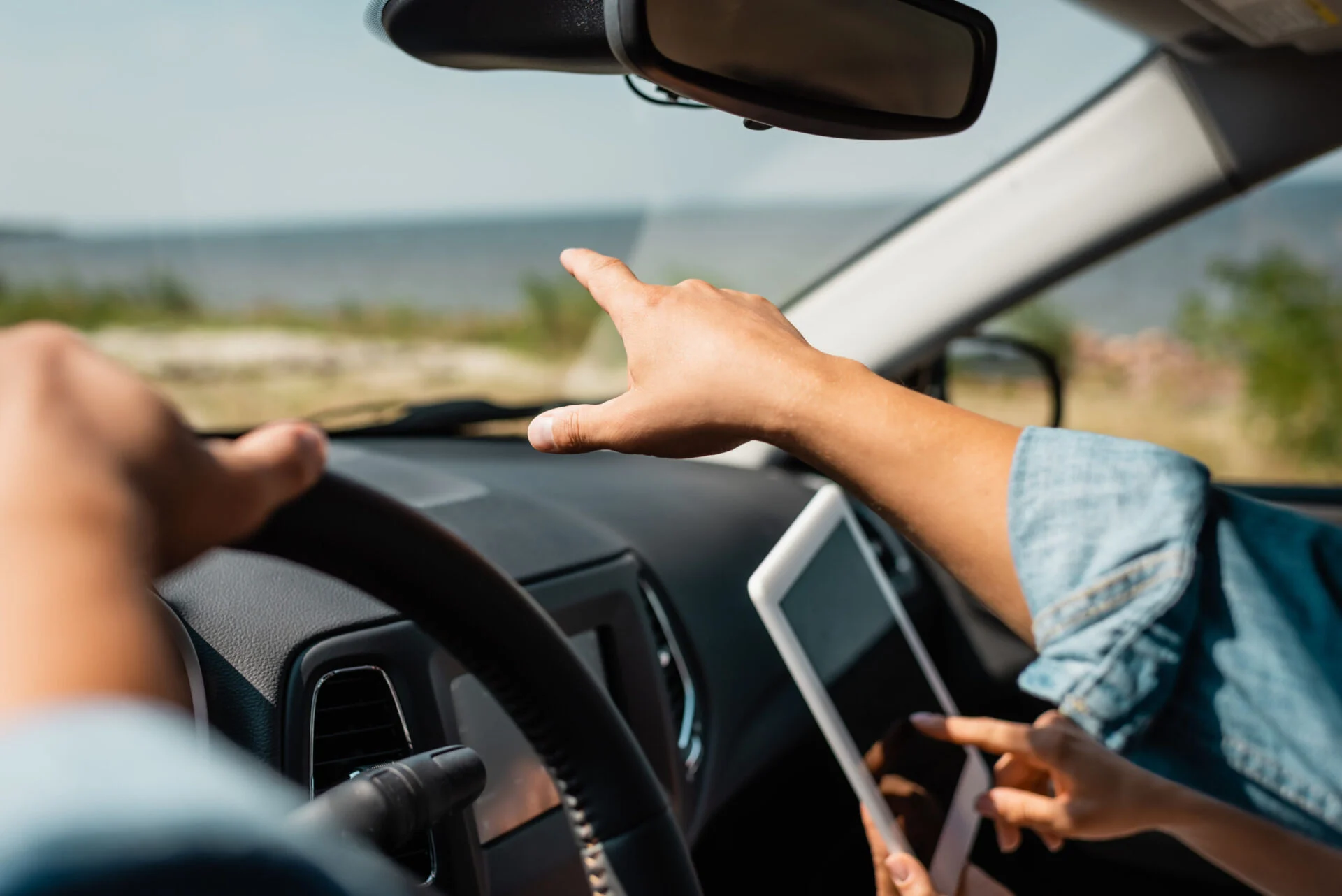 Two people in a car looking at something outside the front window