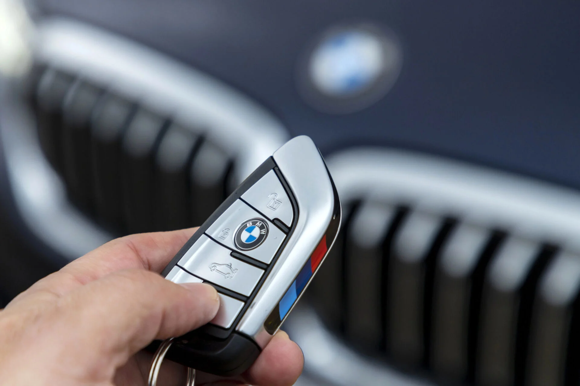 Person holding a key fob to a BMW vehicle