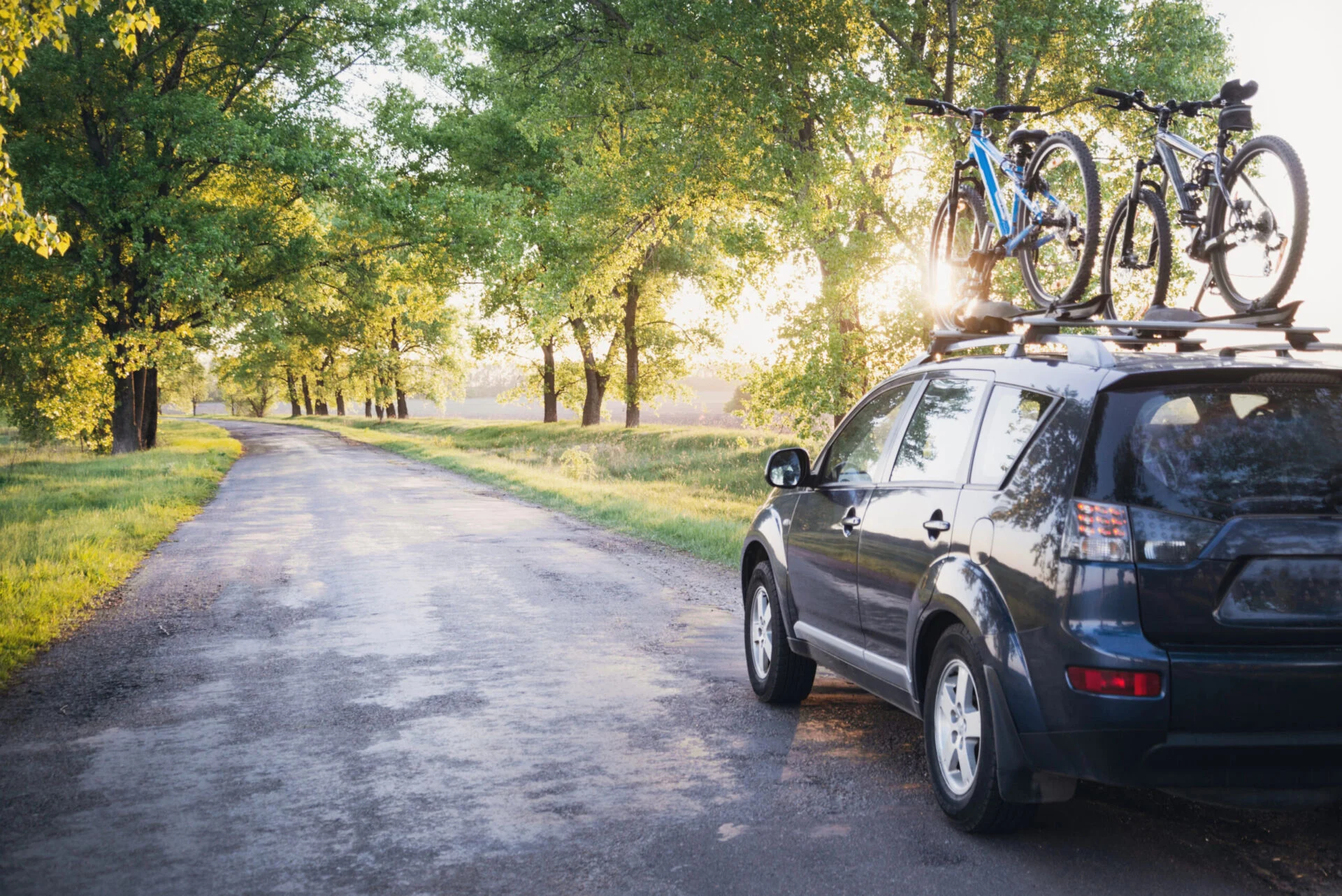 Car on sunny road with bikes on top.