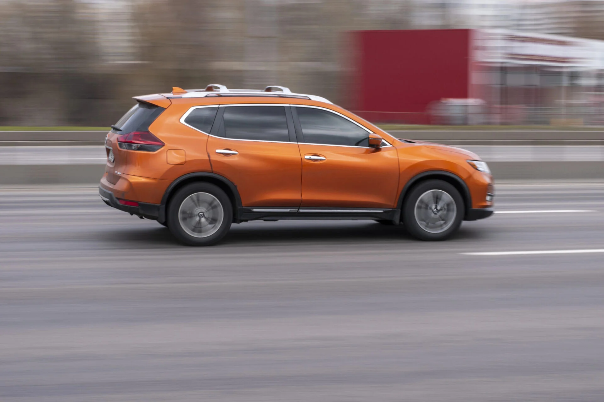Orange Nissan Rogue driving on street