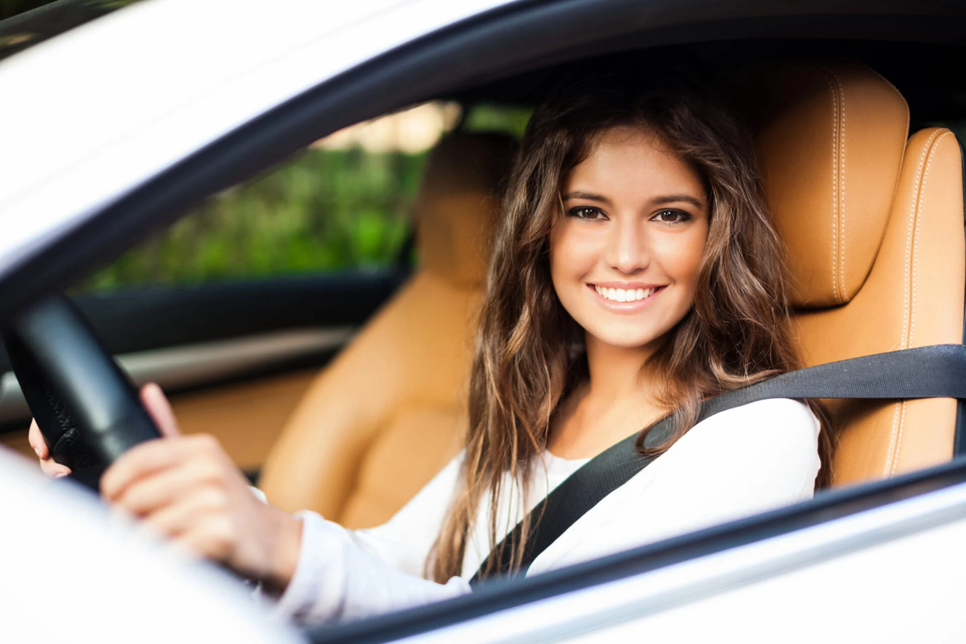 Woman sits in the drivers seat of a car, smiling