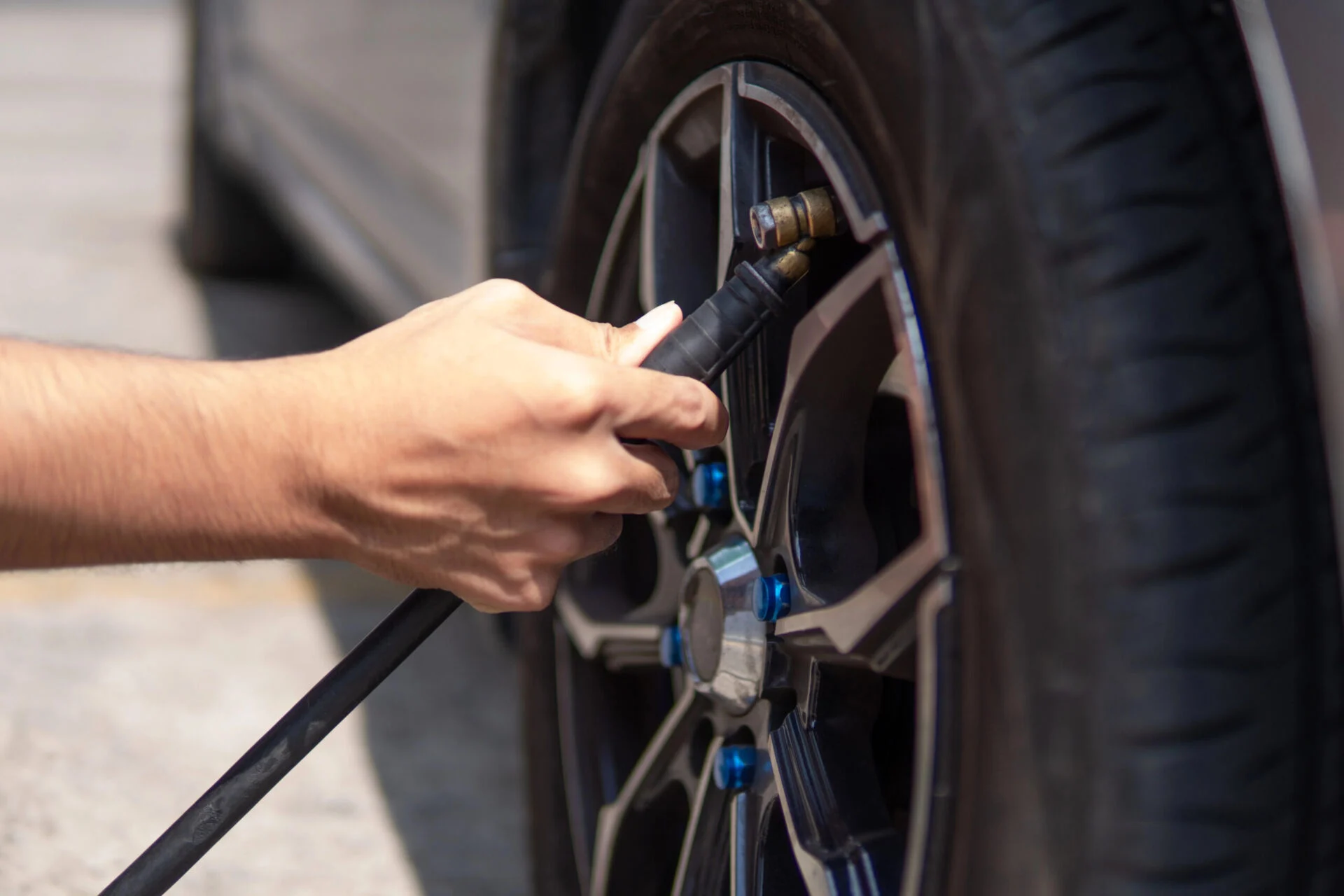 Person filling up a car tire with air