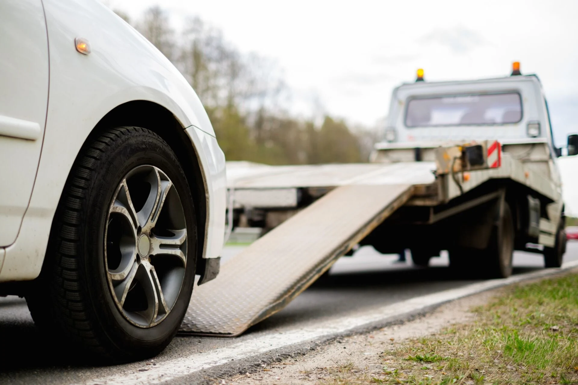 Loading broken car on a tow truck on a roadside.
