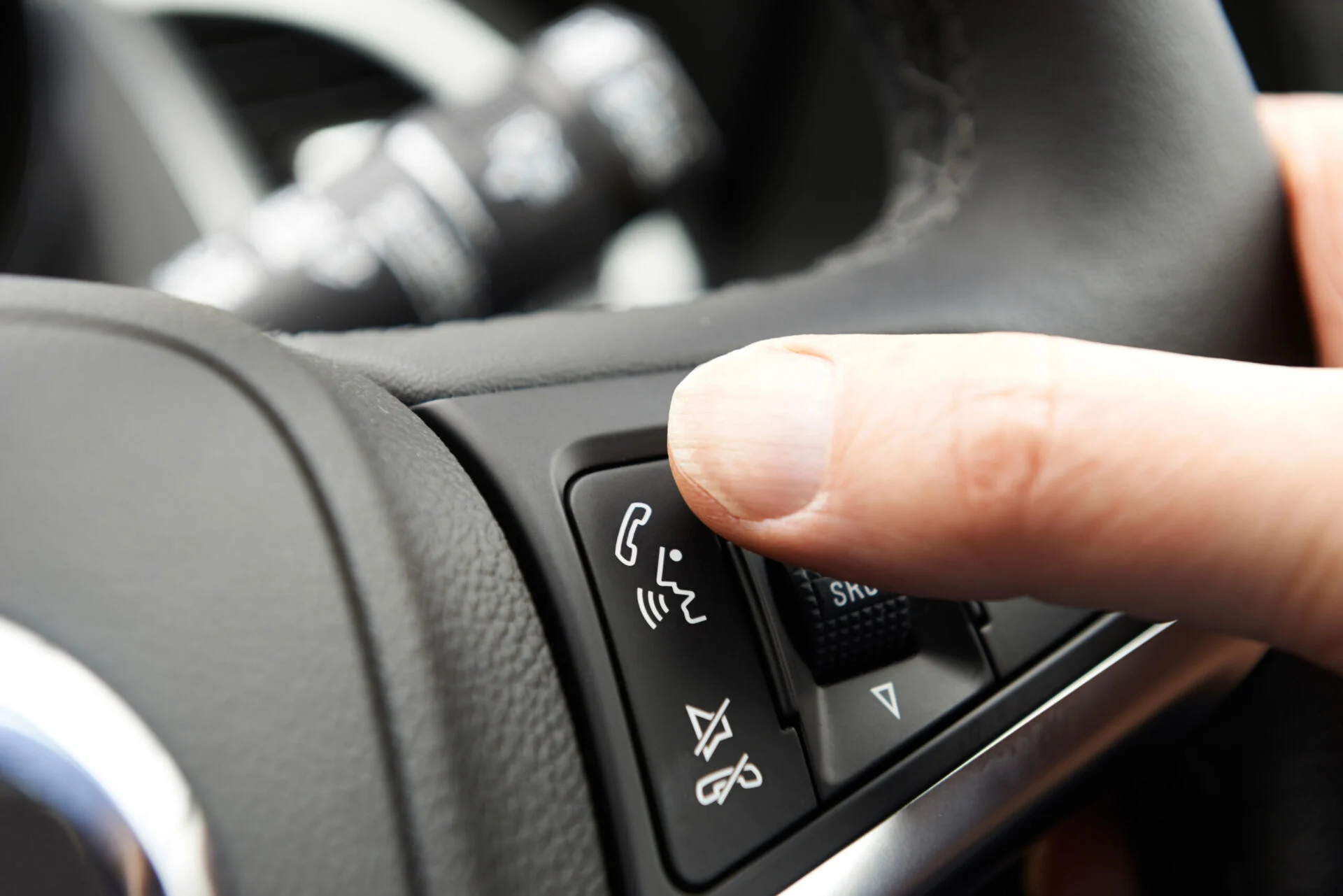Person using the phone speaker button on a car steering wheel