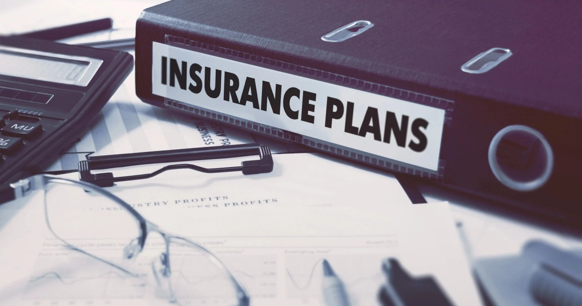 Insurance plans notebook sitting on desk with other office supplies